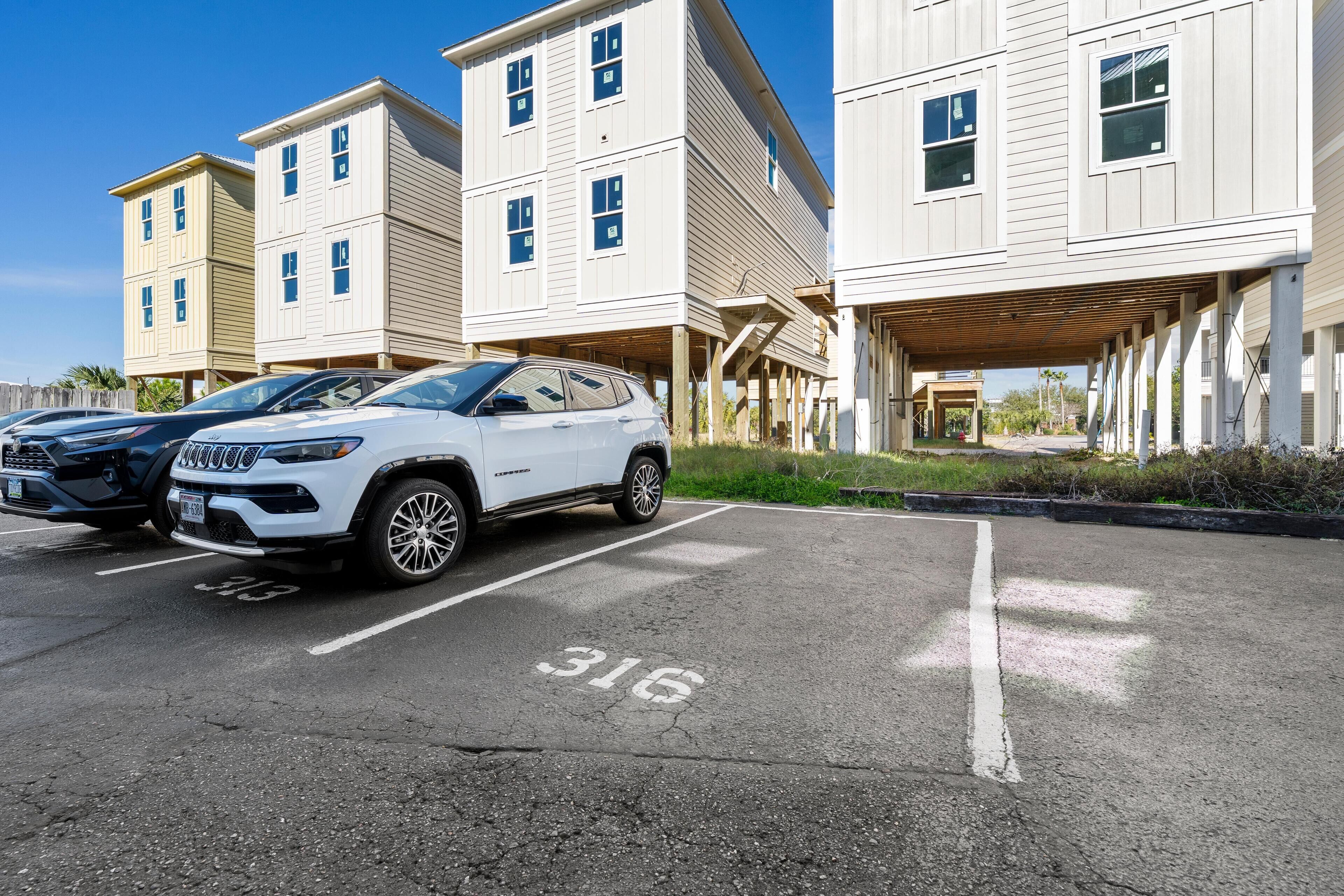 Un parking où sont garés deux SUV blancs.