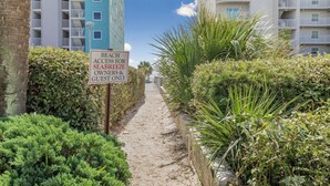 Un sentier mène à une zone située en bord de mer, et un panneau indique que l’accès à la plage est réservé aux propriétaires et aux invités de Seabreeze.