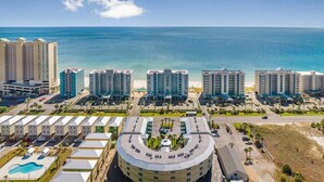 Un complexe hôtelier situé sur la côte, composé de plusieurs immeubles de grande hauteur, d’un parking central et offrant une vue sur l’océan.