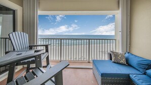 A balcony with a view of the ocean, a table, a chair, and a blue sofa. - Marlin Key 4C (Orange Beach)