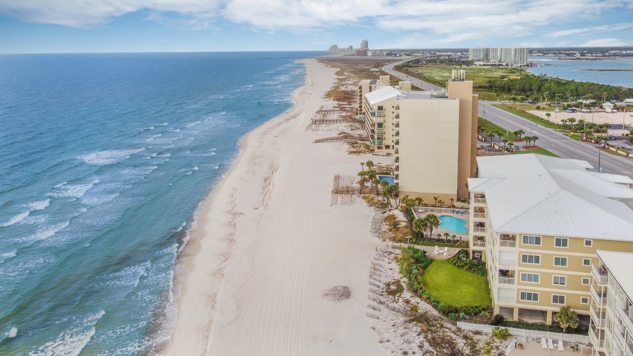 A beachfront hotel with a pool, multiple floors, and a view of the ocean and beach.