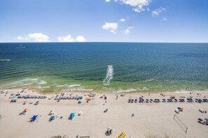 A beach with rows of umbrellas and sun loungers, a clear sky, and a calm sea. - Seawind 1609 (Gulf Shores)