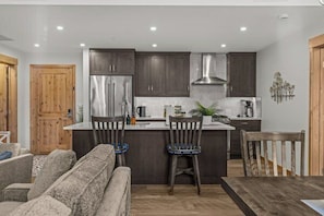 Una cocina moderna con armarios oscuros, electrodomésticos de acero inoxidable y una isla central con asientos.