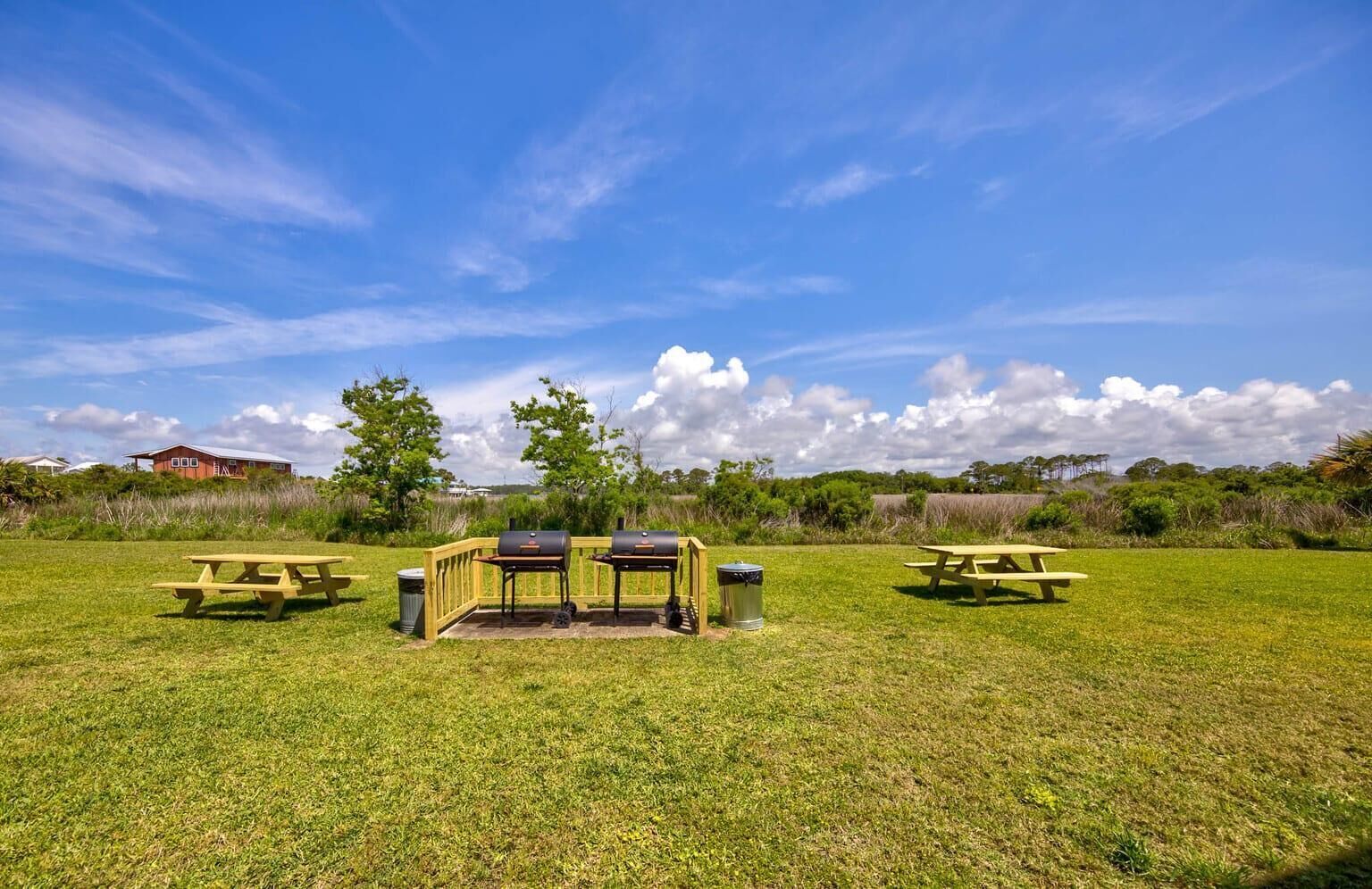 Ein grünes Areal im Freien mit Picknicktischen und Grillmöglichkeiten.