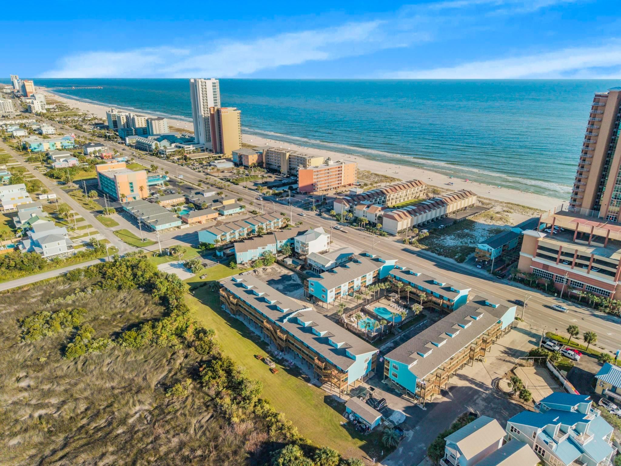 A coastal cityscape with a beachfront hotel, high-rise buildings, and a clear view of the ocean.