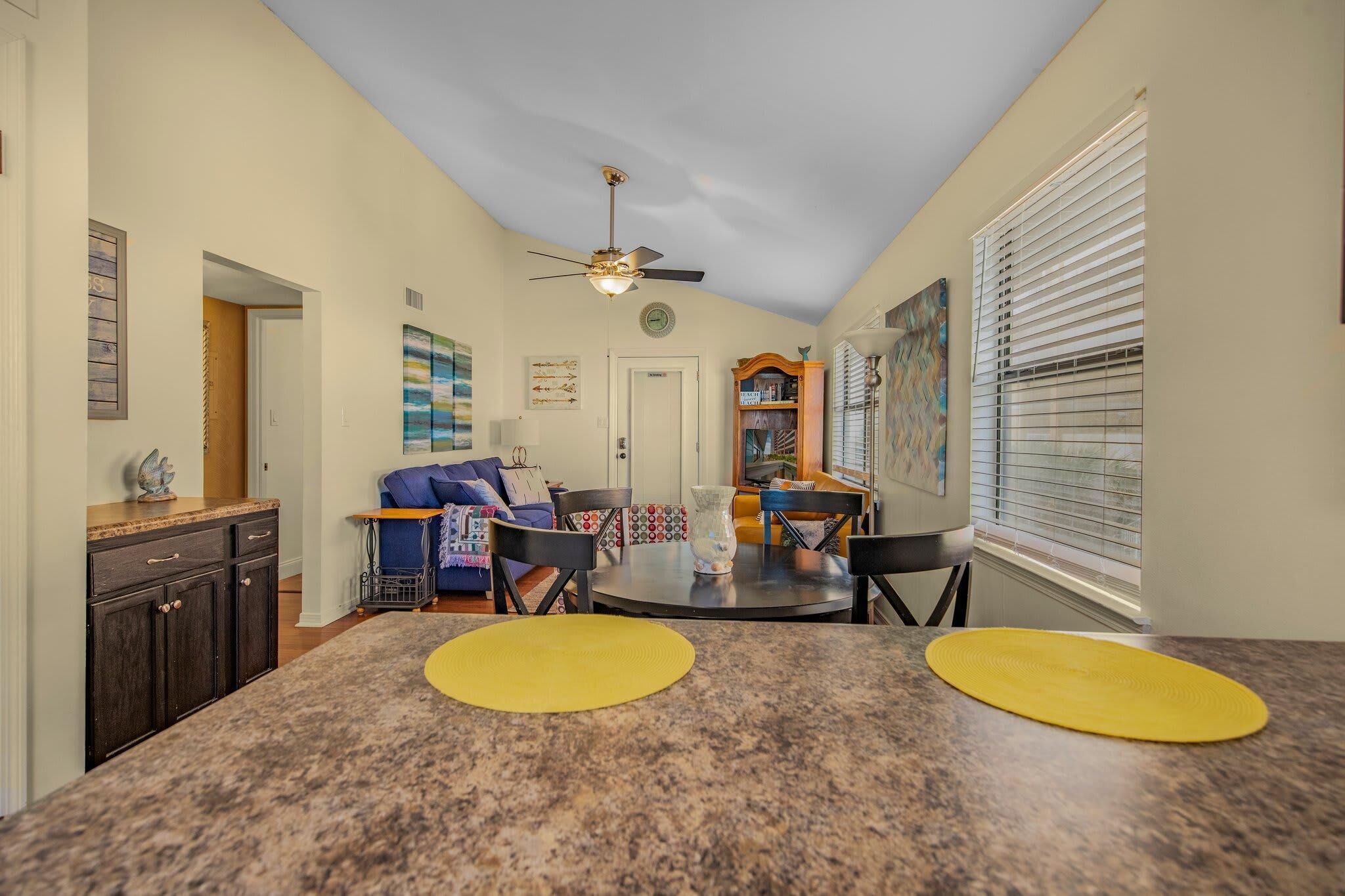 A kitchen with granite countertops, a ceiling fan, and a dining area with a round table and chairs.
