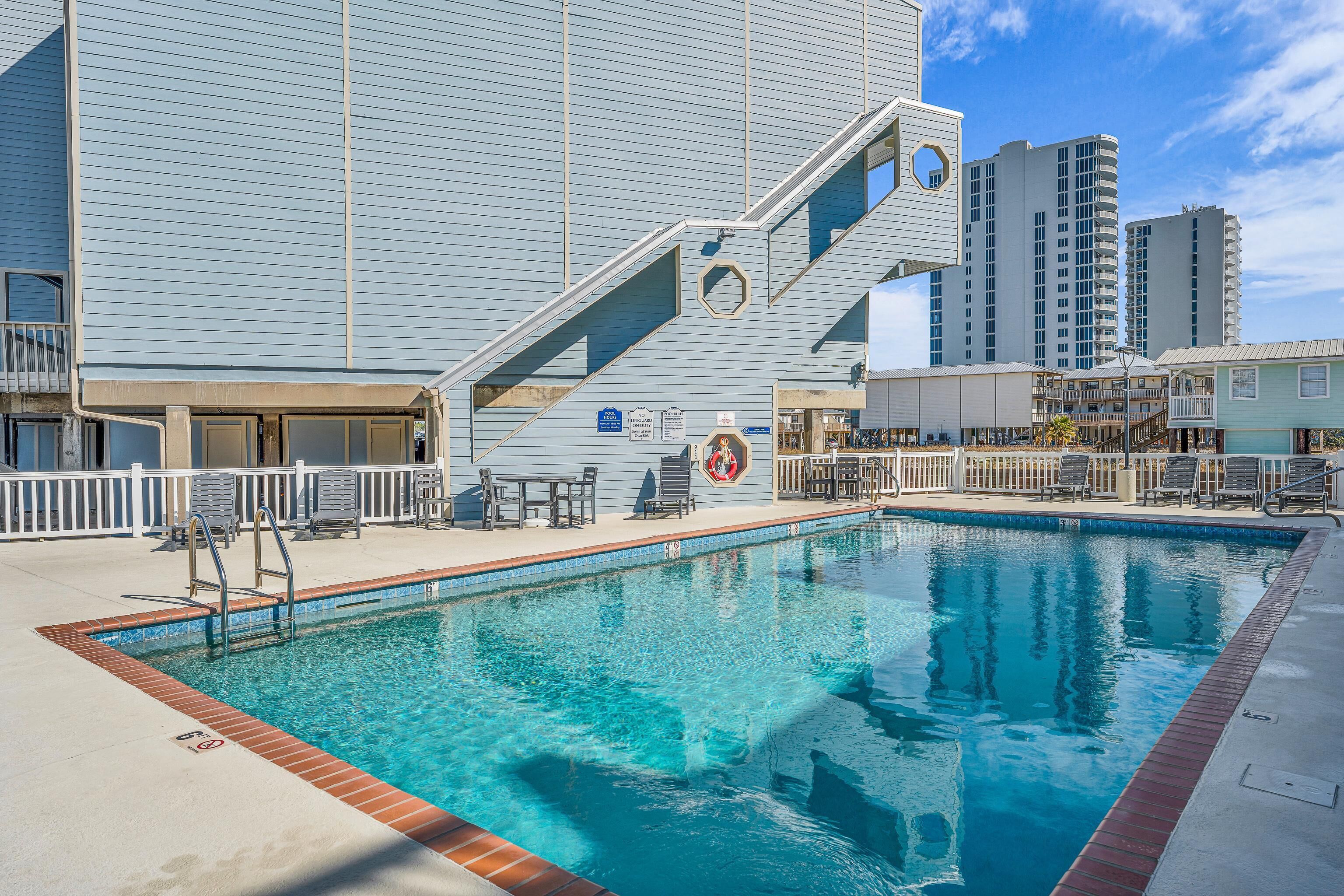 A swimming pool with a blue tiled edge, a lifeguard stand, and a white fence.