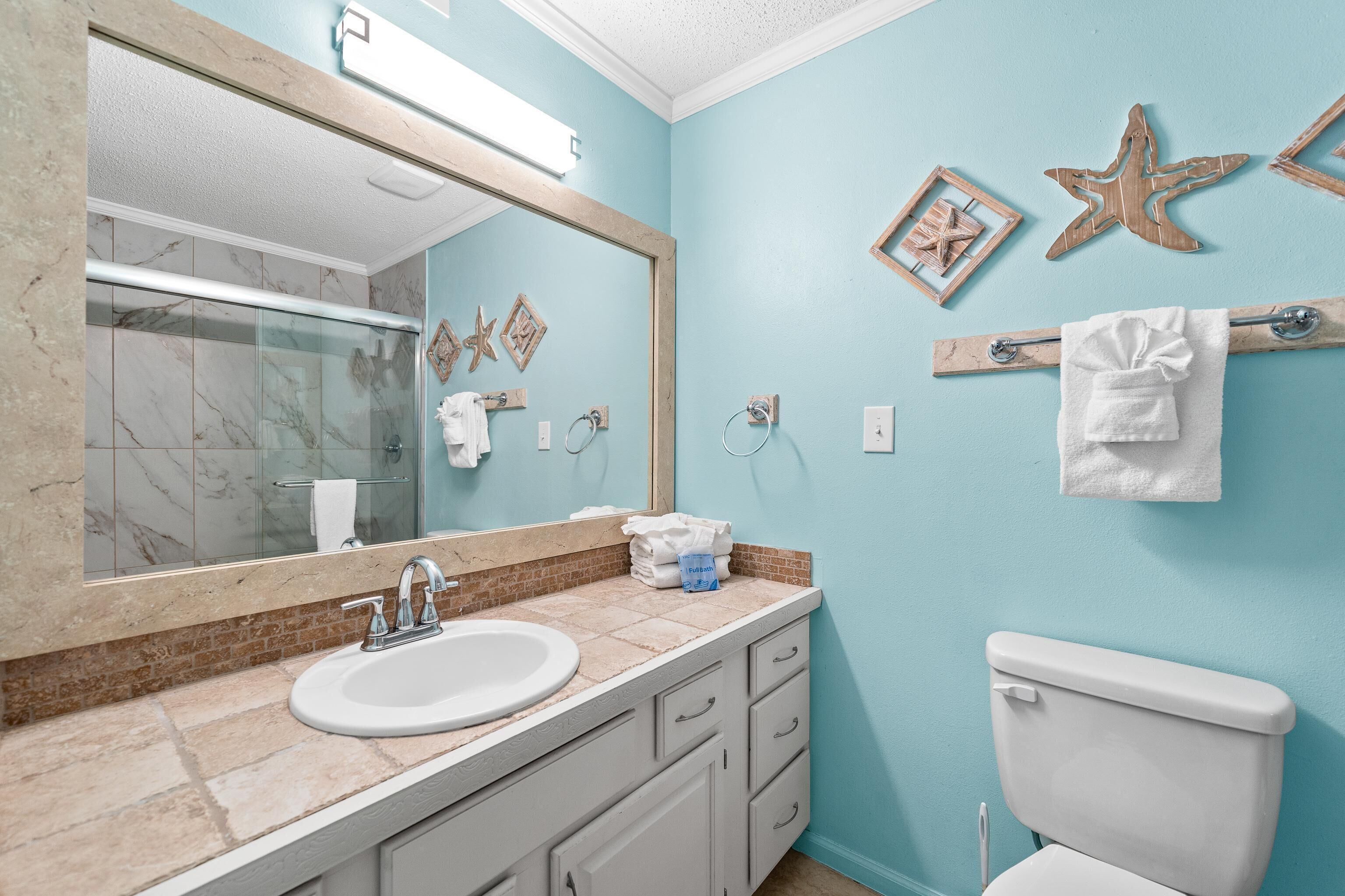 A bathroom with a marble vanity, a white toilet, and decorative starfish wall art.