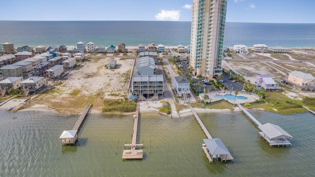 Luftaufnahme eines Küstenresorts mit einem hohen Hotel, Strandhäusern und einer Marina.