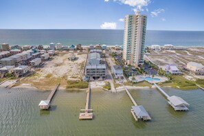 An aerial view of a coastal resort with a tall hotel, beach houses, and a marina. - Summer House West B101 (Gulf Shores)