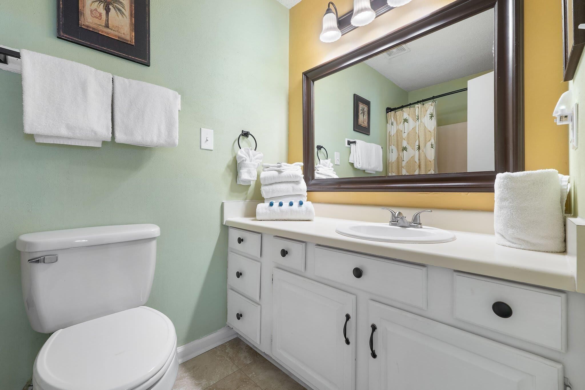 A bathroom with a toilet, sink, and vanity with drawers and a mirror.
