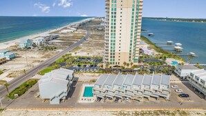 A high-rise hotel with a pool, beachfront view, and a parking area. - Summer House West B102 (Gulf Shores)