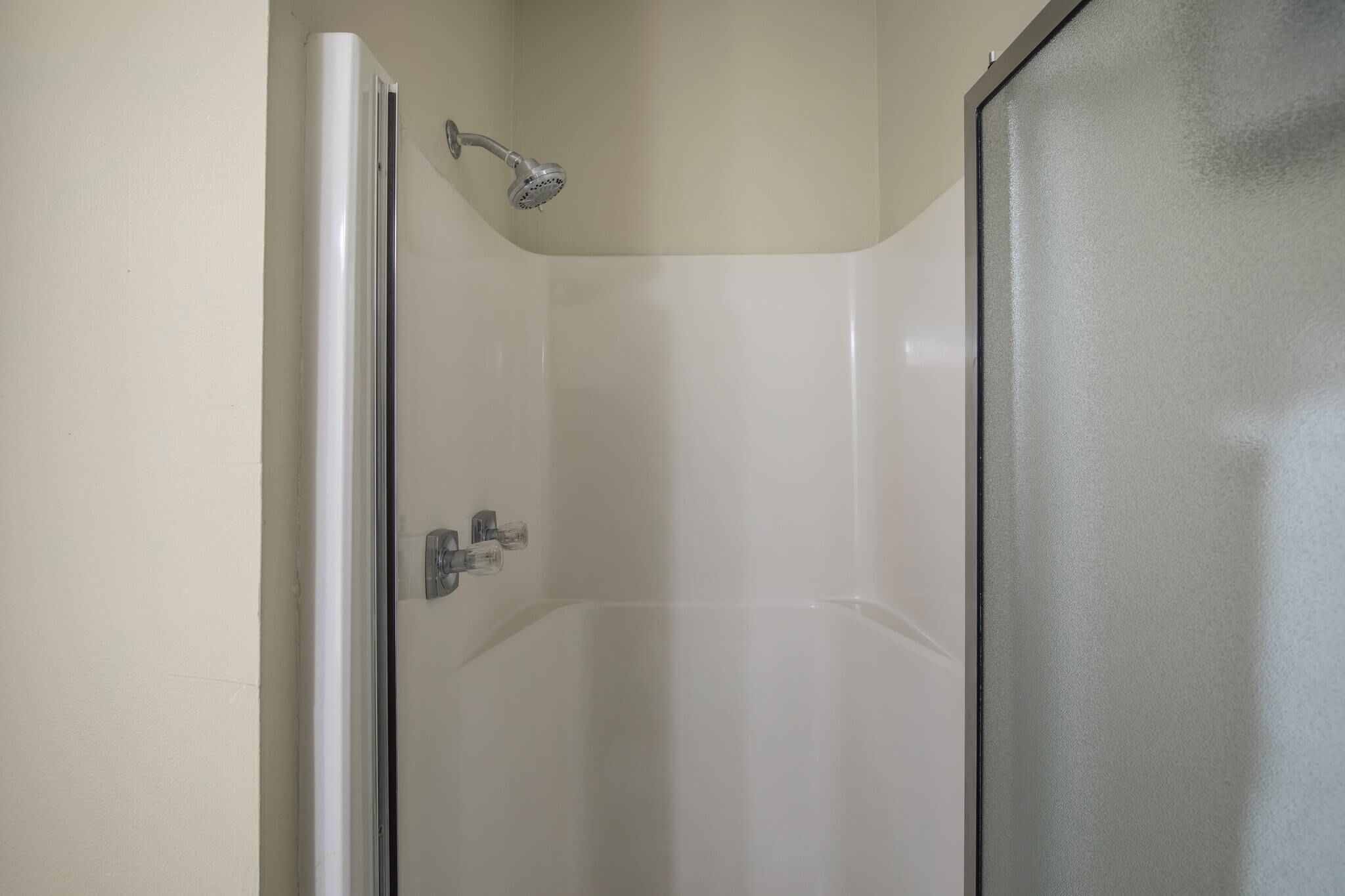 A small, enclosed shower area with a glass door and a handheld showerhead.