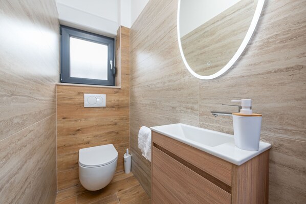 A modern bathroom with a wooden vanity, a white sink, and a toilet.