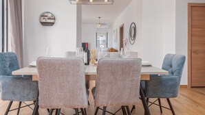 A dining area with a wooden table, four chairs, and a modern chandelier. - Villa Miki Zadarvillas (Polaca)
