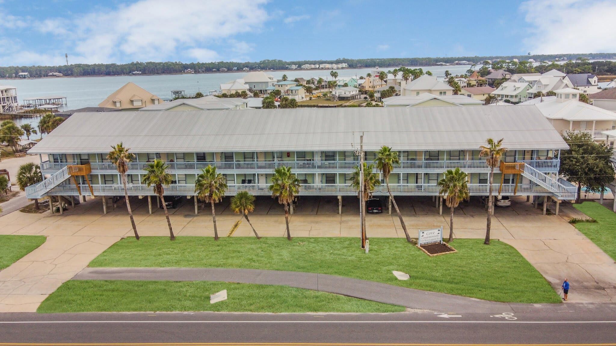 A multi-story hotel with a flat roof, a central courtyard with palm trees, and a view of the sea.