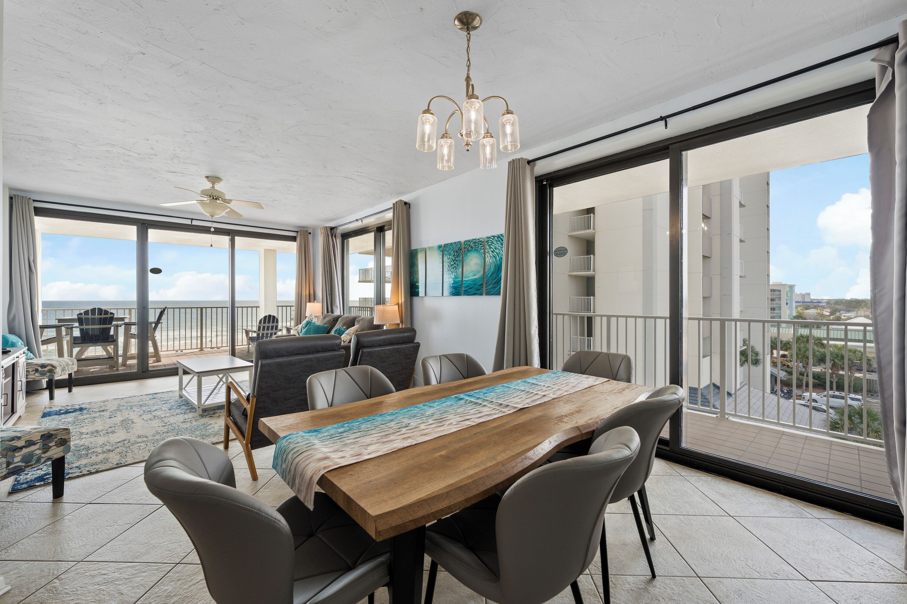 A spacious balcony with a dining area, large windows, and a view of the city.