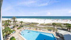 A pool area with lounge chairs, a pool, and a beach view. - Pelican Pointe 506 (Orange Beach)
