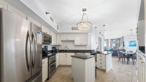 A modern kitchen with stainless steel appliances, white cabinetry, and a central island. - Pelican Pointe 506 (Orange Beach)