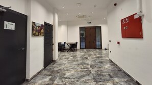 A hallway with a black door, a painting, a fire alarm, and a table with chairs. - Çardak Alti Otel (Arsin)