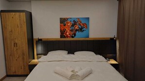 A hotel room with a bed, a wooden wardrobe, a painting on the wall, and a nightstand. - Çardak Alti Otel (Arsin)