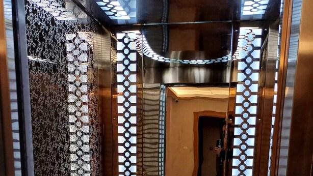 An elevator with a mirrored wall reflecting a clock and patterned design. - Çardak Alti Otel (Arsin)