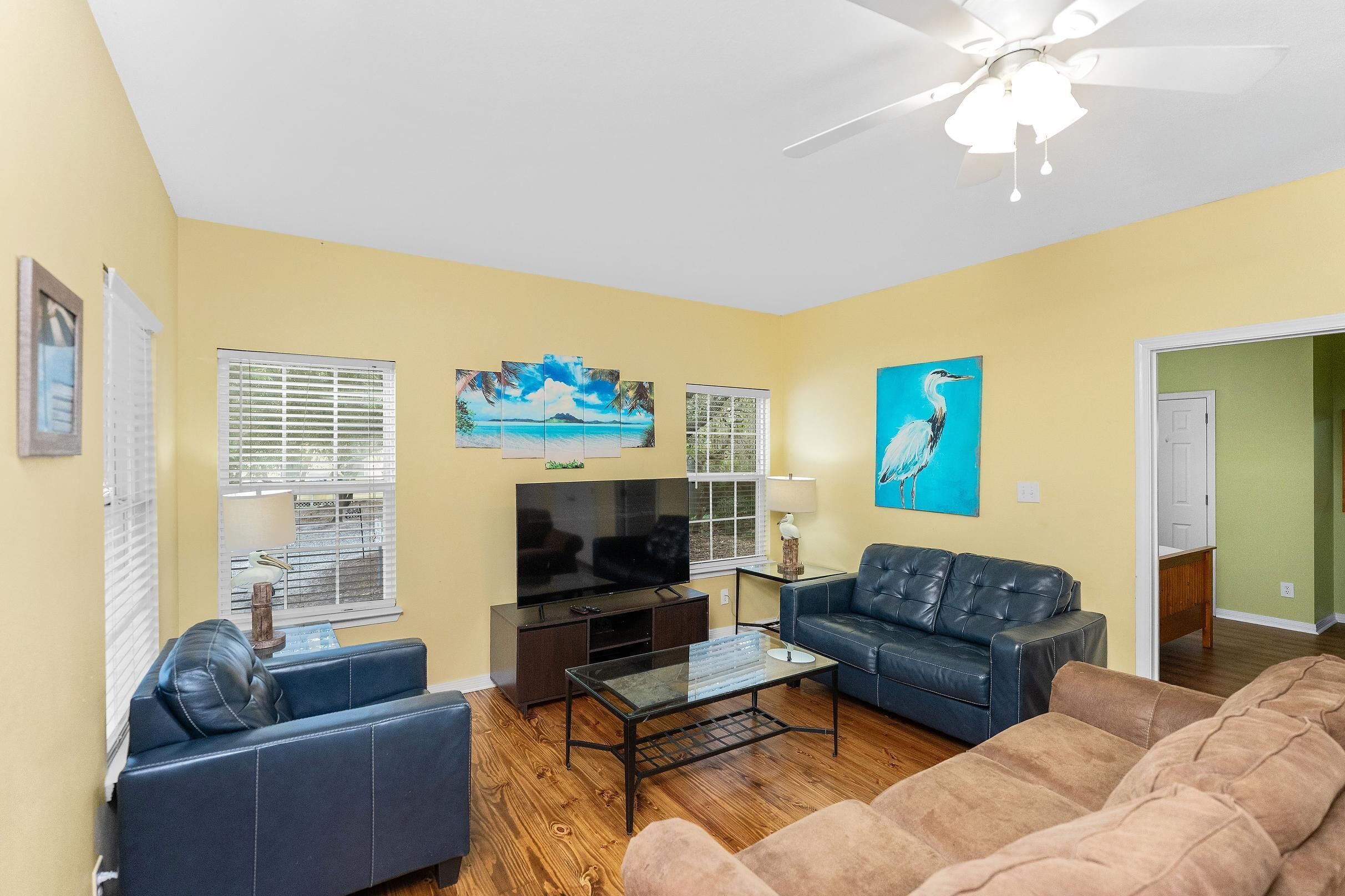 A living room with a ceiling fan, a flat-screen TV, a coffee table, and two sofas.