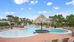 A swimming pool with lounge chairs and a thatched umbrella, surrounded by palm trees and a clear sky. - The Rookery 3504 (Gulf Shores)