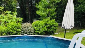 Piscina com deck branco e escada.