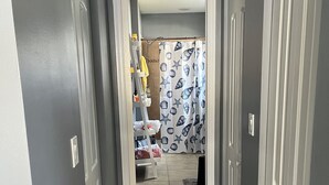 Um corredor com soalho de madeira escura, paredes cinzentas e portas brancas.