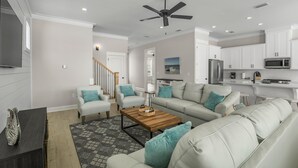 Ein modernes Wohnzimmer mit einer Couch, einem Couchtisch und einem Fernseher. Eine Treppe führt in einen anderen Raum.