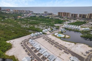 An aerial view of a coastal area with residential buildings, a marina, and a large body of water.