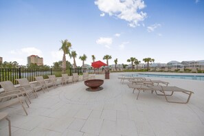 A rooftop pool area with lounge chairs, a fire pit, and a red umbrella. - Summer Salt 24170 (Orange Beach)