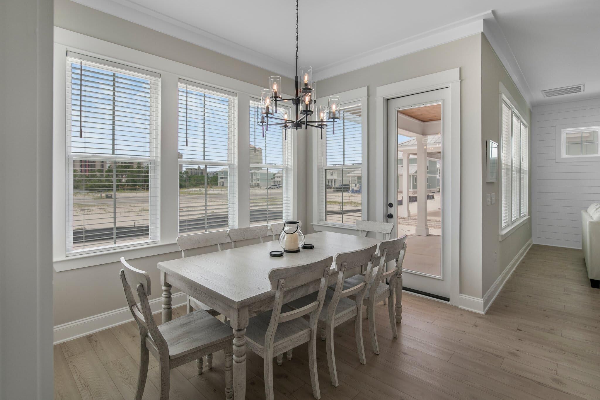 A dining area with a large table, six chairs, and a chandelier.