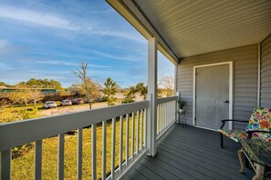 Relax on the covered porch with a glass door leading to the interior, a small table, and a chair.