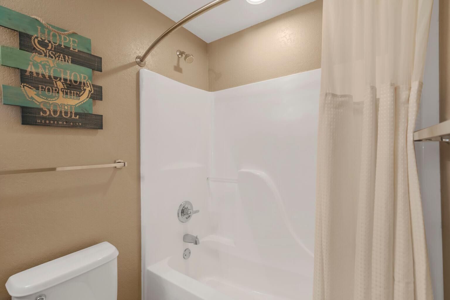 Un baño con una bañera blanca, un inodoro y una cortina de ducha.