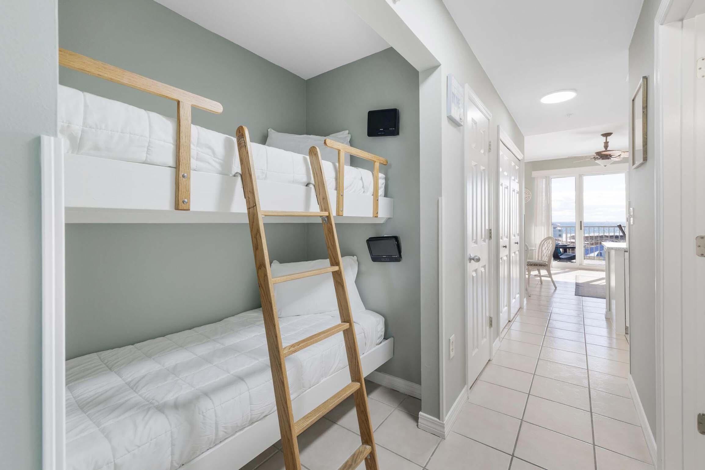 Ein Zimmer mit Etagenbetten, einer Himmelsleiter, einem Fernseher und Blick ins Freie.