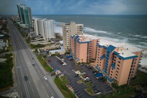 An aerial view of a coastal hotel with multiple buildings, a parking lot, and a road. - Four Seasons 103e (Orange Beach)