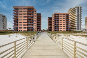 A boardwalk leading to beachfront high-rise buildings with balconies and a sandy beach. - Four Seasons 103e (Orange Beach)