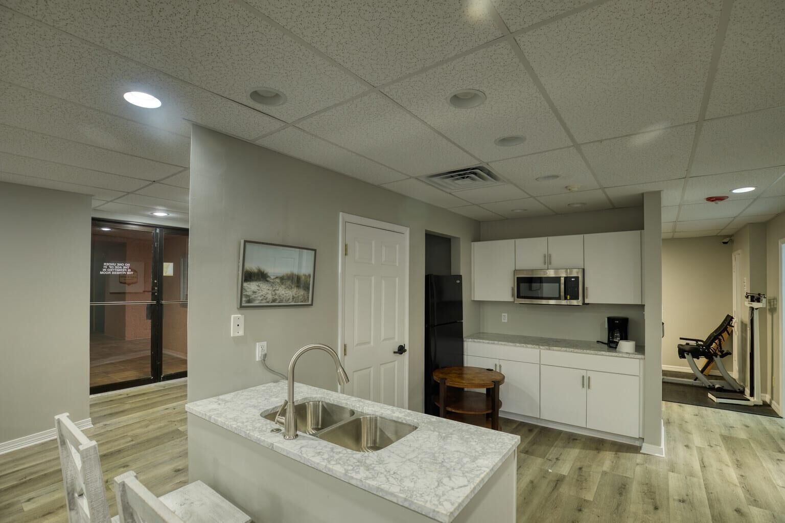 A modern kitchen with a marble countertop, stainless steel sink, and a built-in microwave.