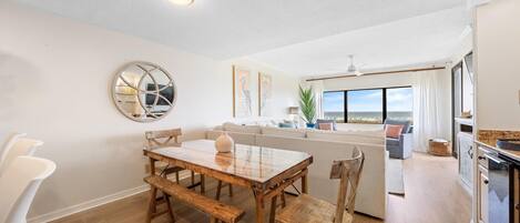 A modern kitchen with a dining area, a large window, and a view of the outdoors.