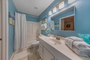 A bathroom with a white sink, a toilet, a shower curtain, and a mirror.