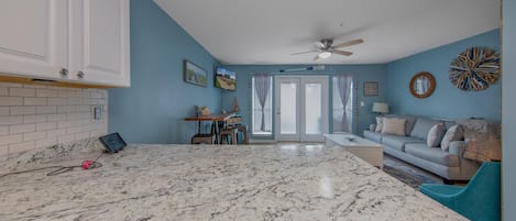 A spacious kitchen with a marble countertop, white cabinets, and a ceiling fan.