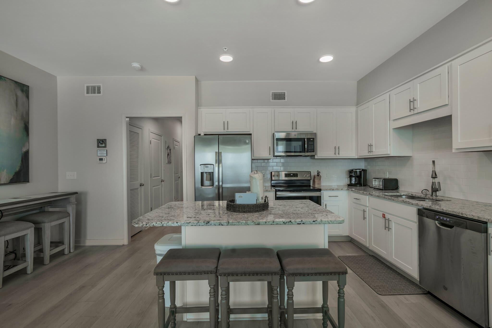 A modern kitchen with white cabinets, stainless steel appliances, and a granite countertop.