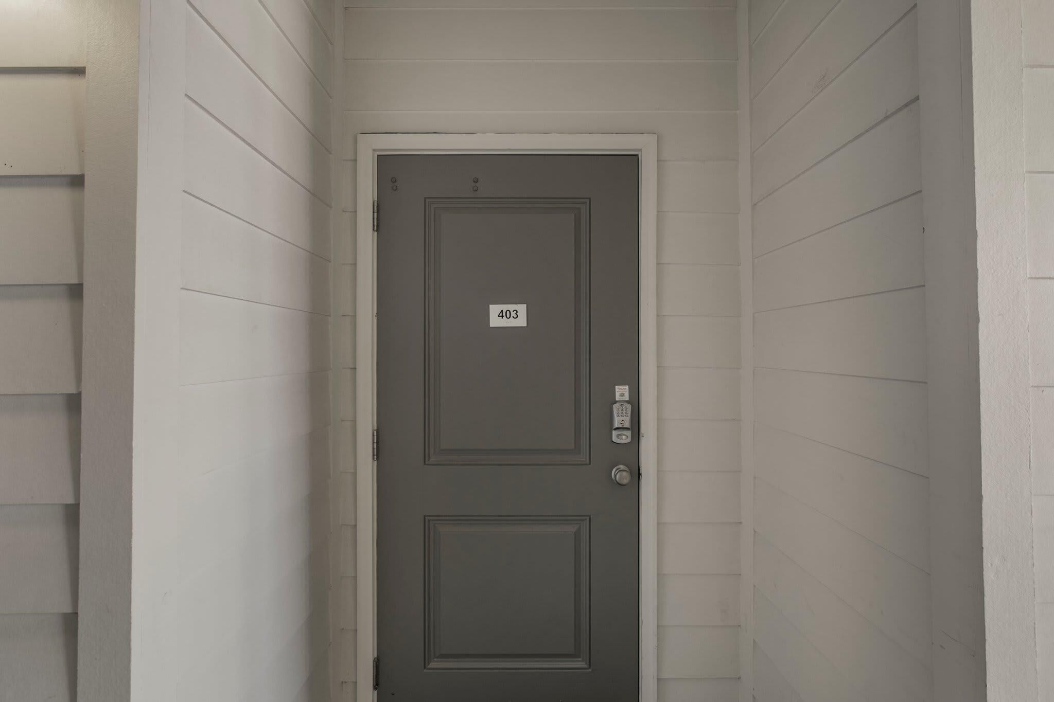 A gray door with a number plate labeled "403" and a keypad lock.