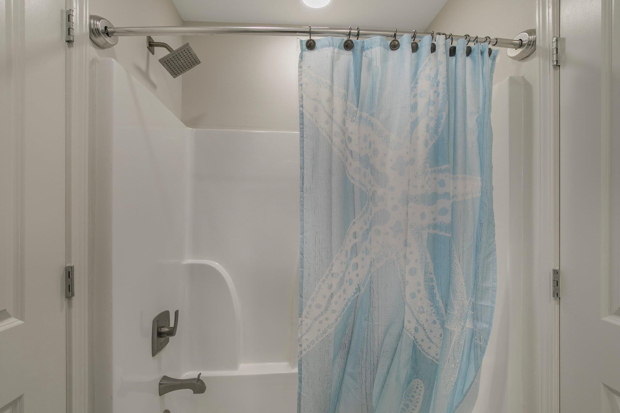 A shower with a curtain, a handheld showerhead, and a wall-mounted control panel.