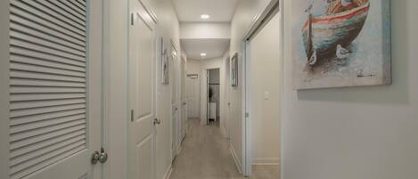 A hallway with white doors, a painting of a boat, and a ceiling light.