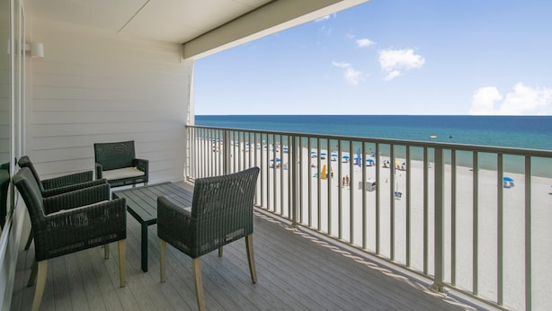 Ein Balkon mit Korbmöbeln und Blick auf den Strand.