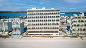 A high-rise hotel with multiple balconies, a swimming pool, and a view of the beach and water. - Crystal Shores W 301 (Gulf Shores)