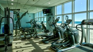 A gym with cardio machines, weight machines, and a TV screen. - Crystal Shores W 301 (Gulf Shores)